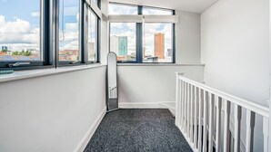 A corner room with a view of buildings, a white railing, and a dark carpet. - Spacious 3BR Duplex | Sleeps 7 | 2 En-Suites | Secure Parking | 3 Balconies (Birmingham)