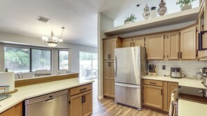 Una cocina con armarios de madera, un refrigerador de acero inoxidable y un lavavajillas.