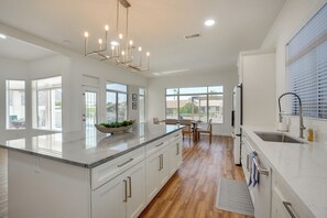 Una cocina moderna con una isla grande, armarios blancos y un comedor con vistas.