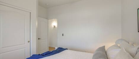 A bedroom with a bed, a ceiling fan, a wall-mounted light, and a door.