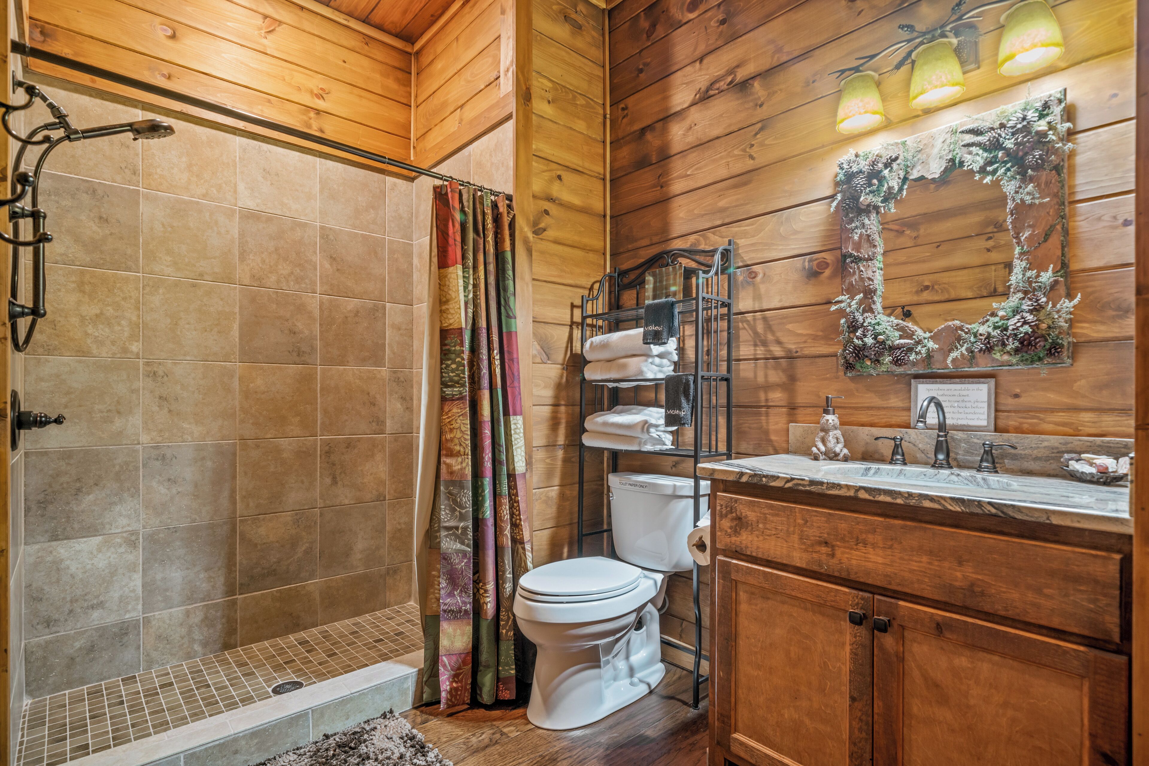 A wooden cabin bathroom with a shower, toilet, and sink.