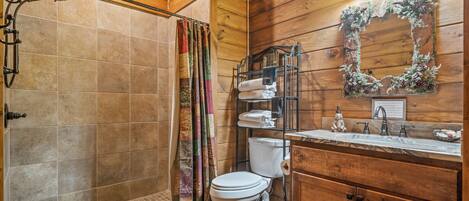 A wooden cabin bathroom with a shower, toilet, and sink.