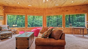 A wooden cabin interior with a sofa, armchair, and a desk. - Forest Sanctuary, a Lakeside Retreat (Blue Ridge)