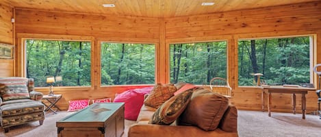 L’intérieur d’un chalet en bois, avec un canapé, un fauteuil et un bureau.