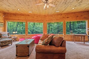 Interior de una cabaña de madera con sofá, sillón y escritorio.