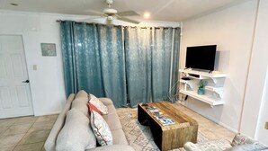 A living room with a sofa, a coffee table, a television, and a ceiling fan. - Spacious  2 Separate Units apartment Sleeps 8 in beautiful Rodney Bay with AC (Rodney Bay)