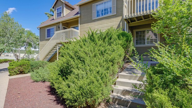 A multi-story residential building with a balcony, a staircase, and a well-maintained garden.