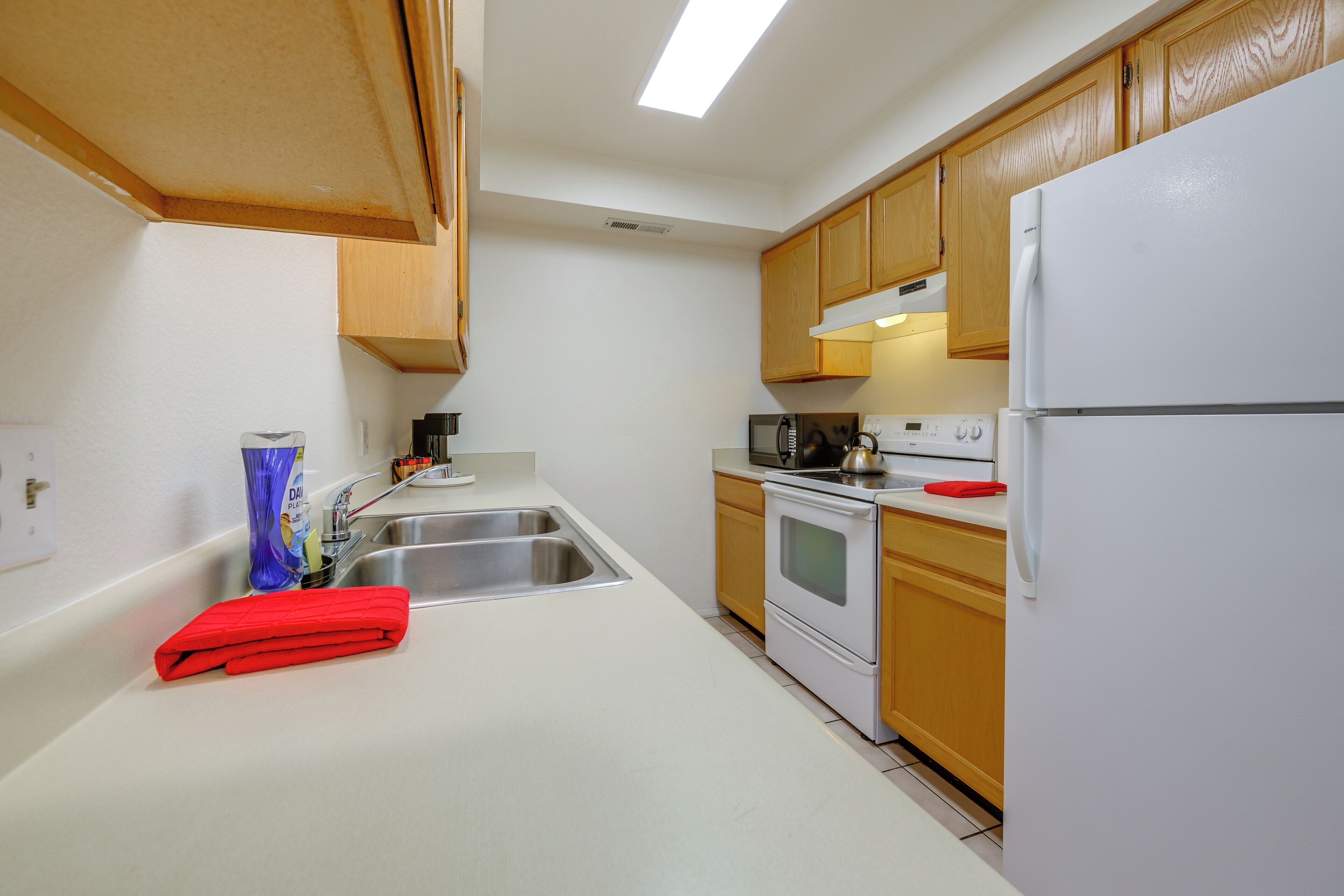 Una cocina con armarios de madera, un refrigerador blanco, una estufa y un lavaplatos.