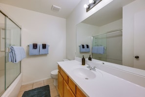 A bathroom with a glass shower enclosure, a white sink, wooden cabinets, and a large mirror. - Shop, Dine, Hike, Explore Dtwn! Flagstaff Getaway (Flagstaff)