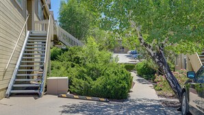 A residential street with a staircase leading to a building, a tree-lined sidewalk, and parked cars.