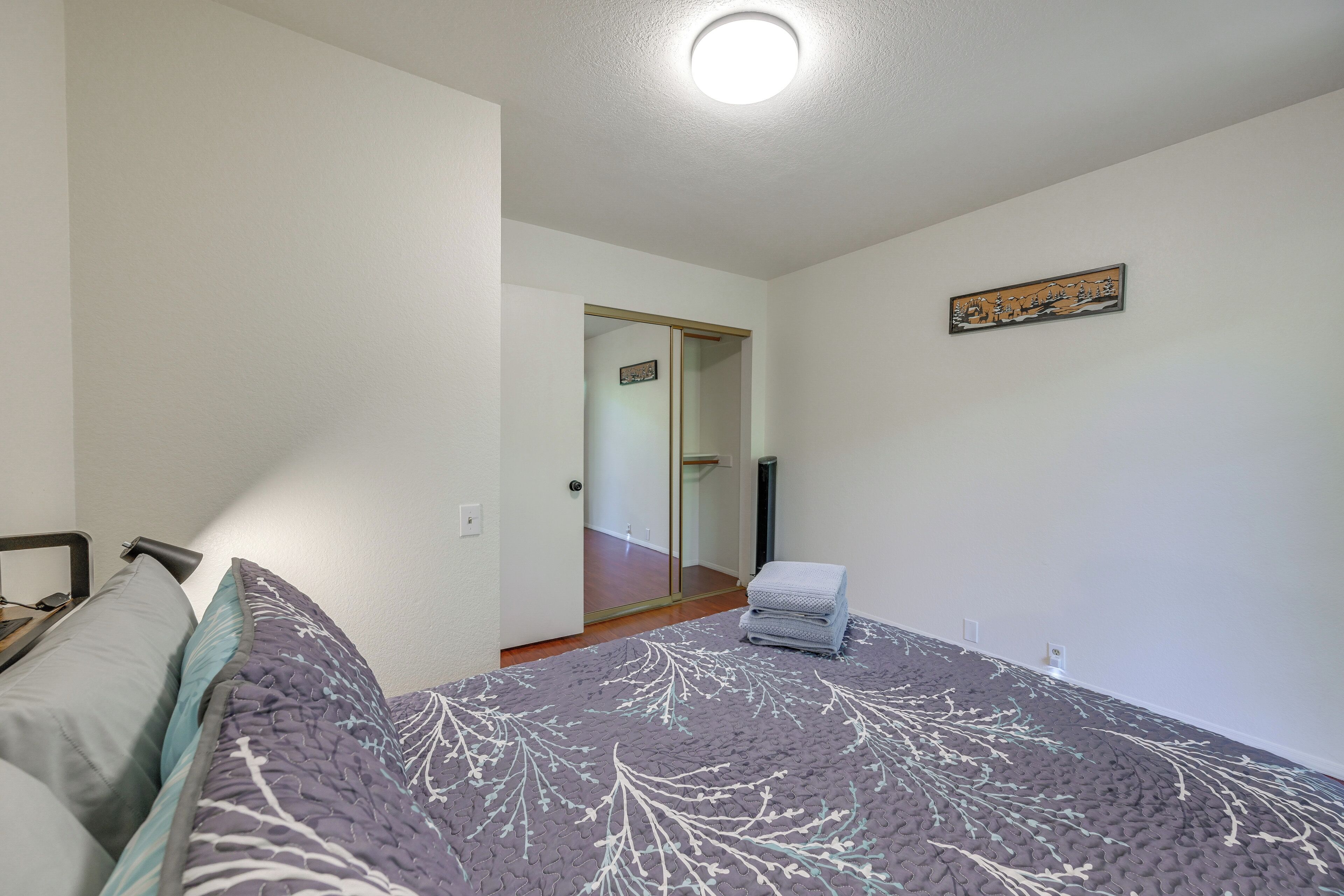 A bedroom with a bed, a chair, a door, and a small table.