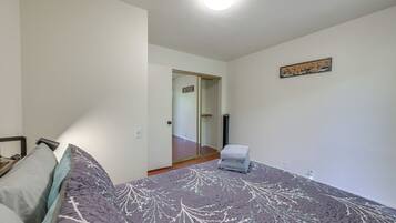 A bedroom with a bed, a chair, a door, and a small table.