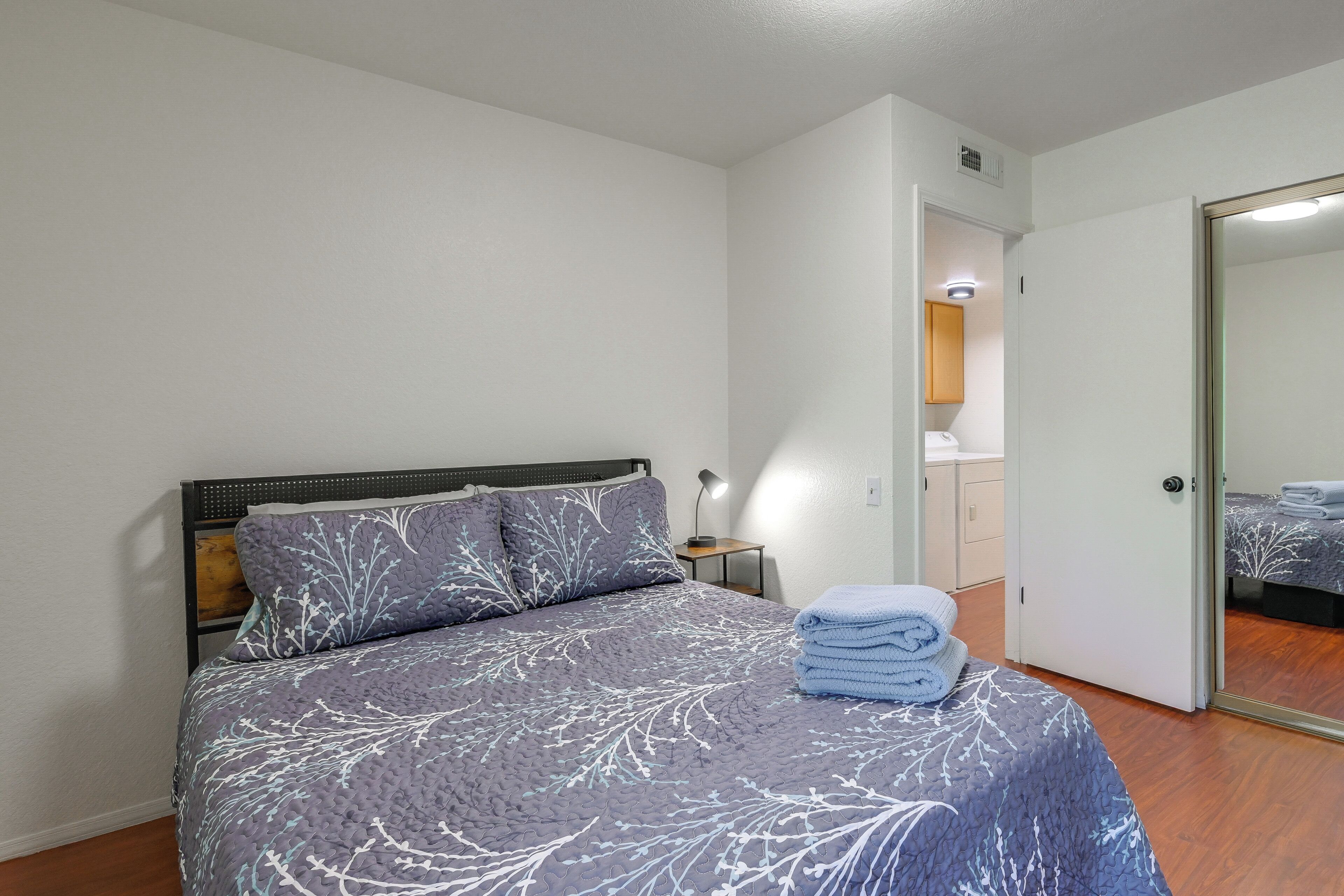 Une chambre à coucher avec un lit, une table de chevet, une lampe, une porte et un miroir.