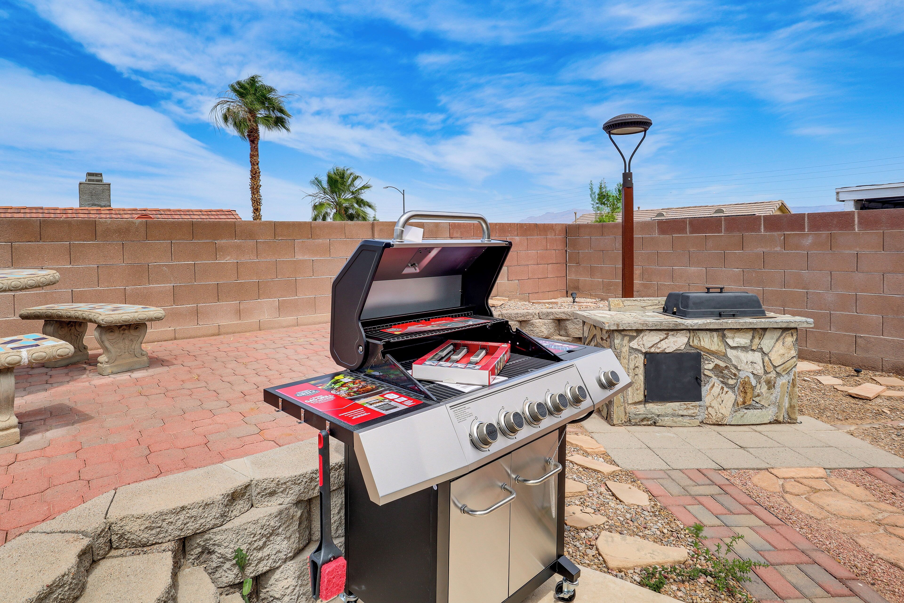 An outdoor grill area with a stone table, a barbecue grill, and a stone oven.