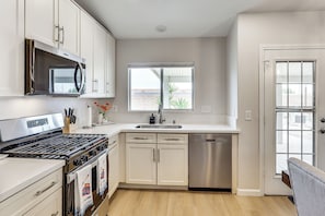 A modern kitchen with white cabinets, a stainless steel stove, a microwave, and a dishwasher. - Poolside Chills, Hiking Thrills! Las Vegas Retreat (Las Vegas)