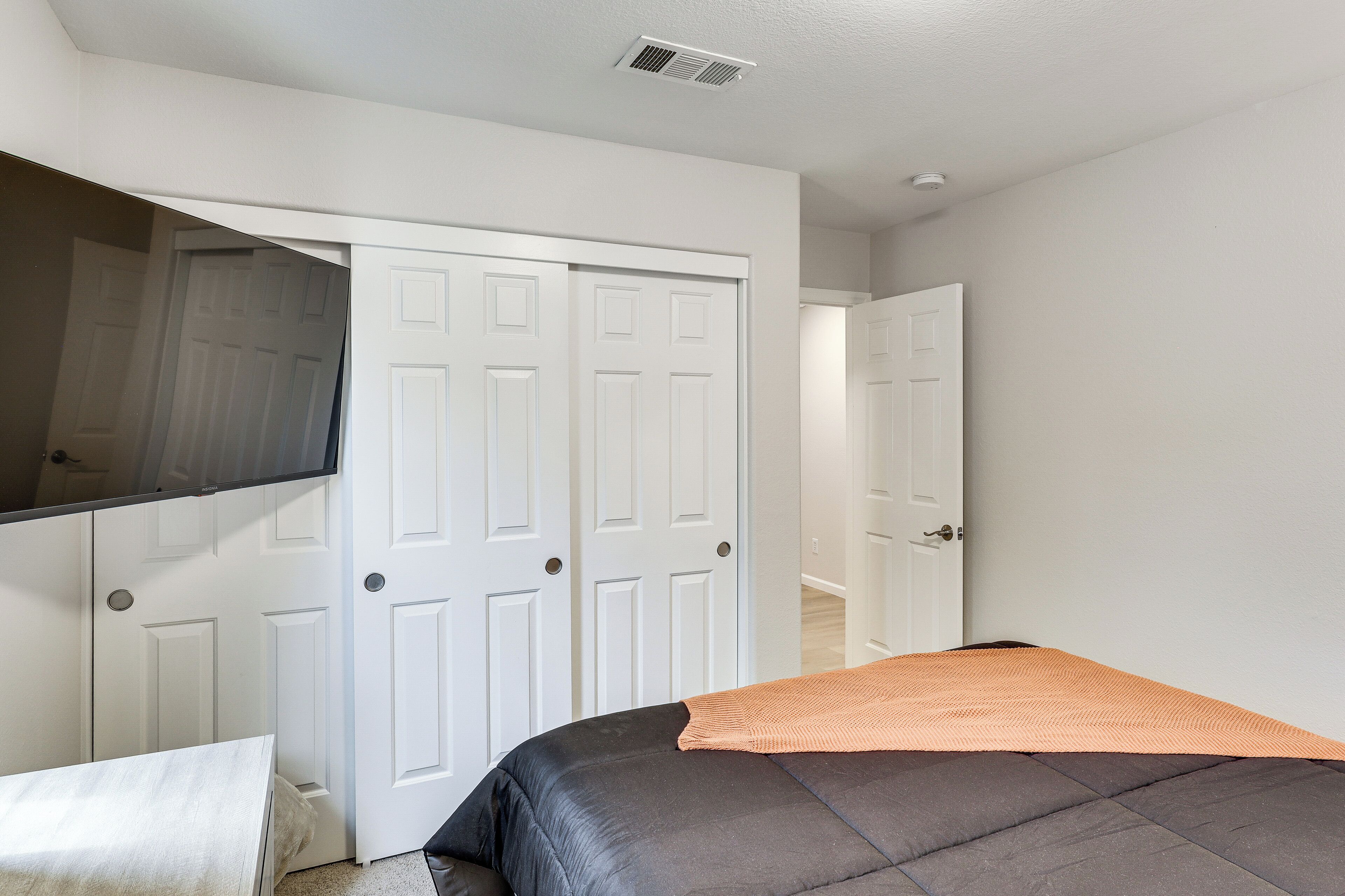 A bedroom with a bed, a white door, and a white wall.
