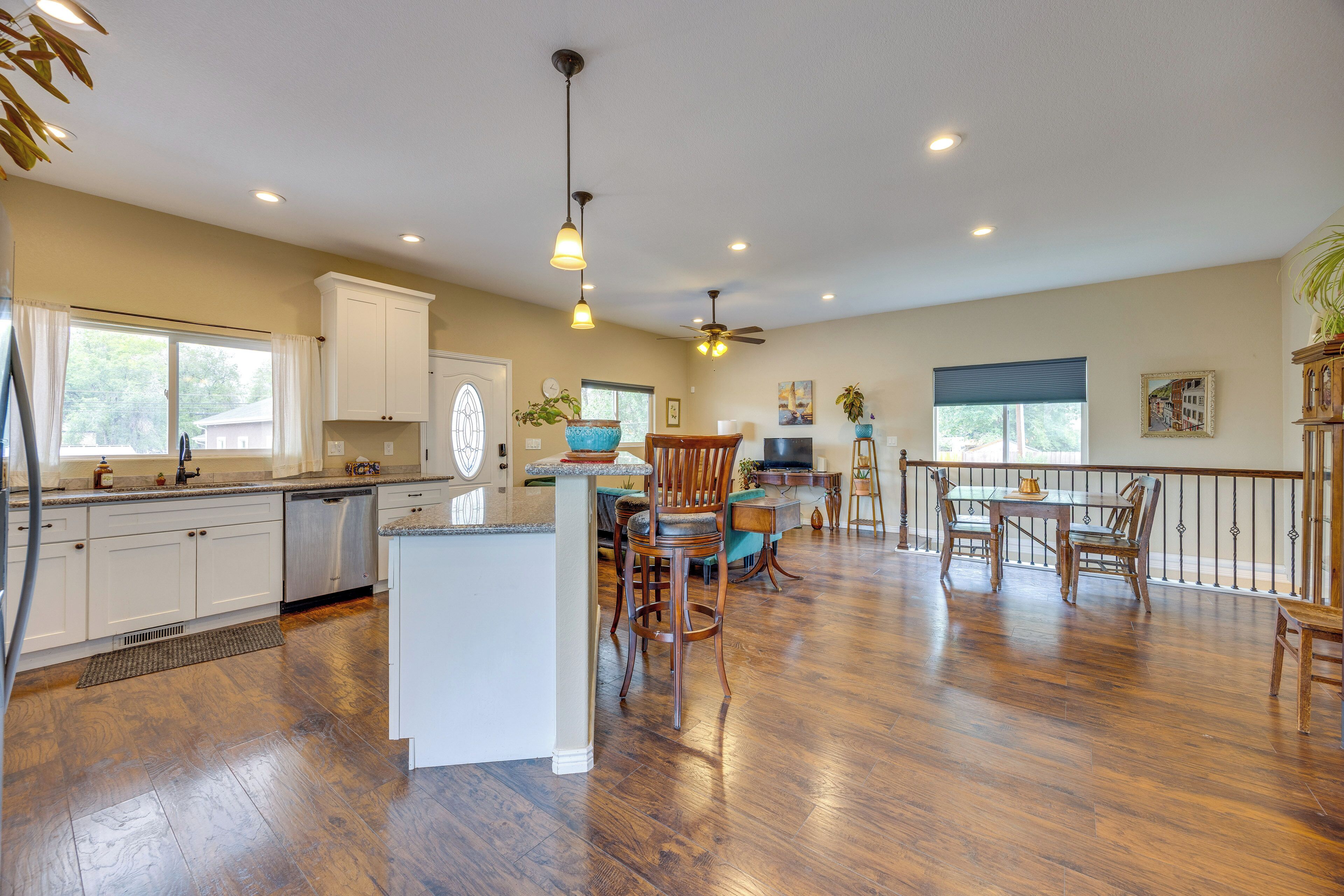 A spacious kitchen with wooden flooring, white cabinetry, and a dining area with a table and chairs.