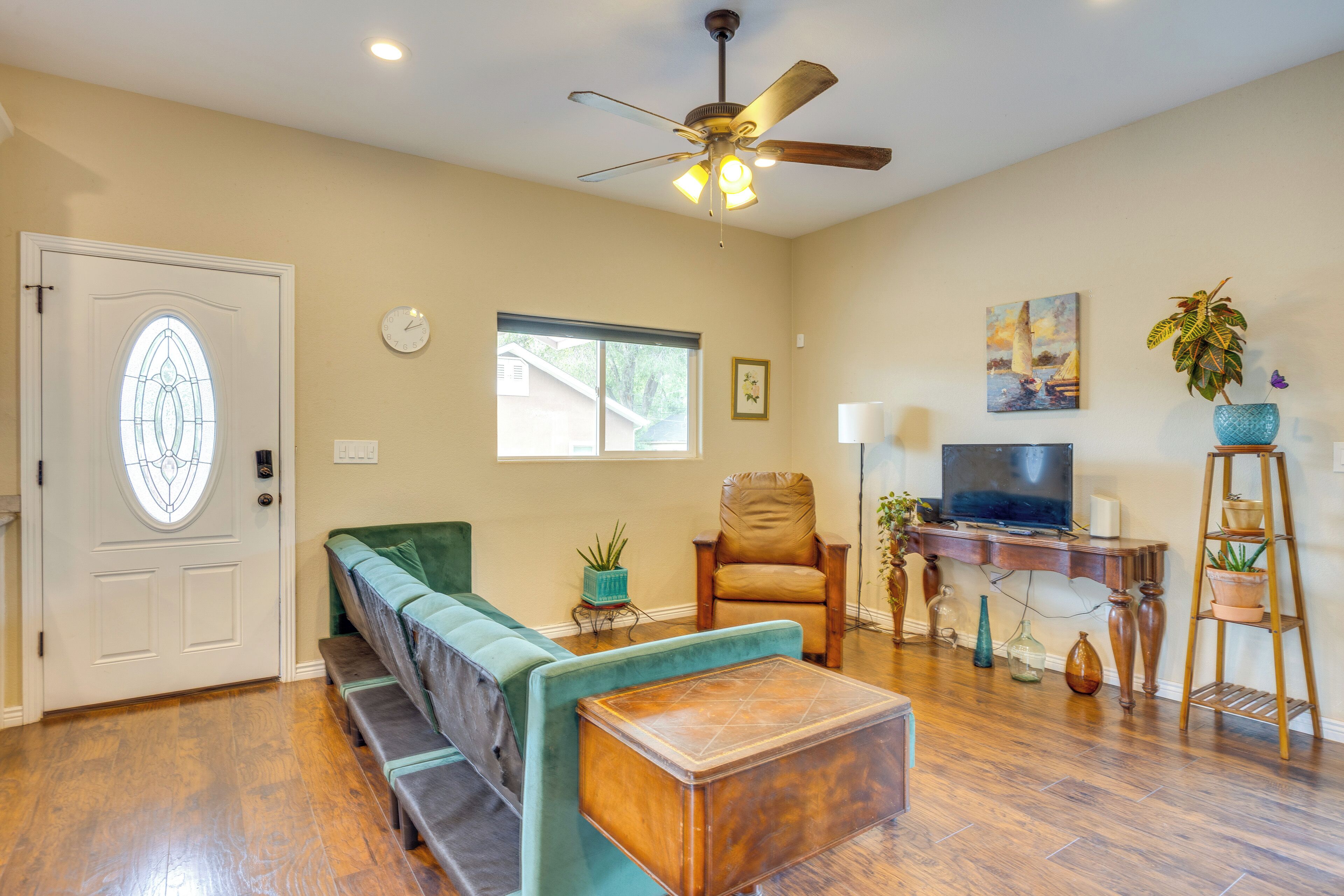 A living room with a sofa, a coffee table, a TV, a chair, and a ceiling fan.