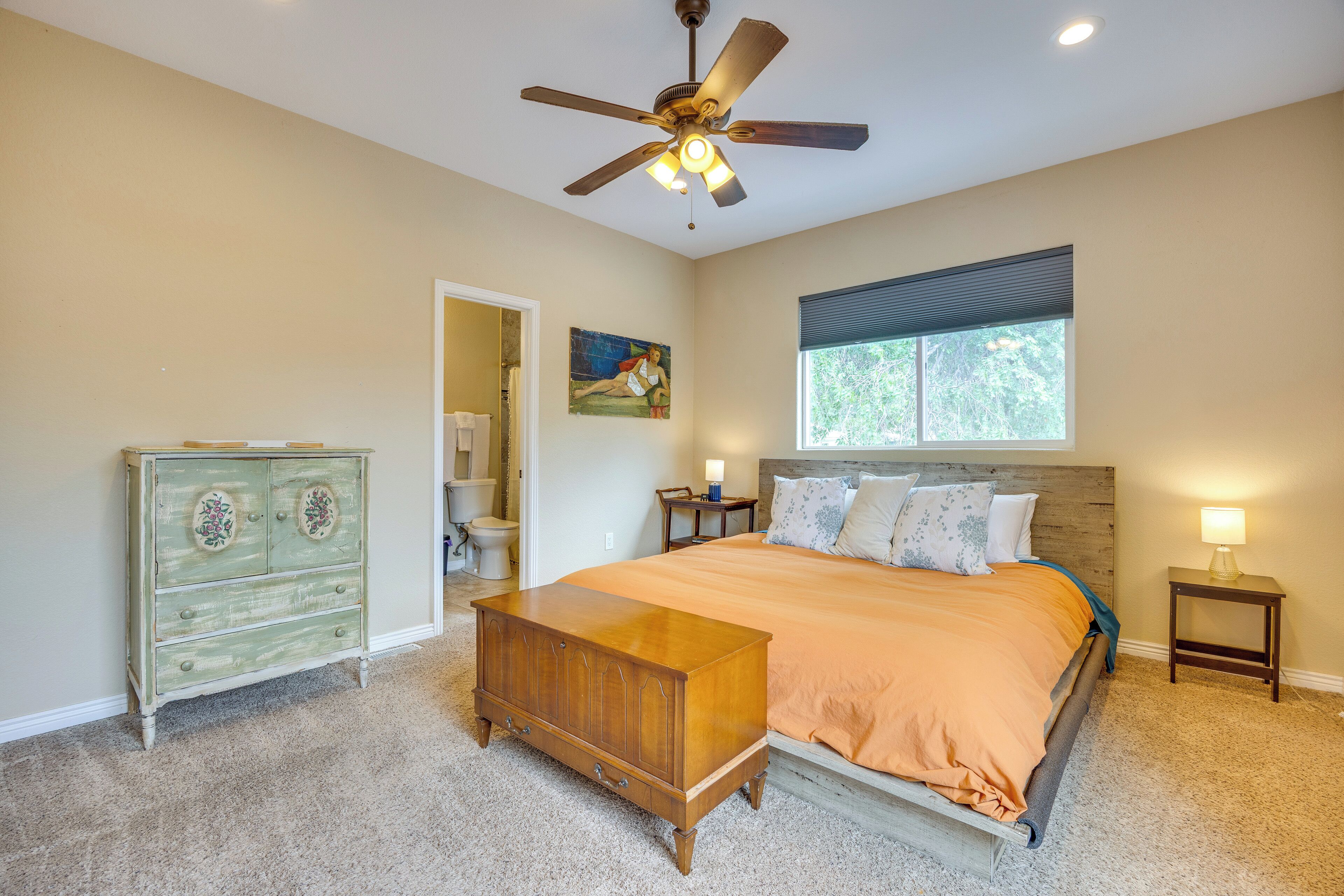 A bedroom with a bed, dresser, ceiling fan, window, and nightstand.
