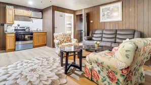 Eine moderne Küche mit integrierten Geräten, ein Essbereich mit floralem Bezug und ein Wohnzimmer mit Ledersofa.