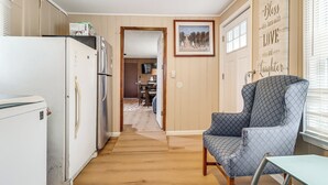 Eine Küche mit Kühlschrank, ein Essbereich mit Tisch und Stühlen sowie ein Flur, der zu einem Wohnzimmer führt.