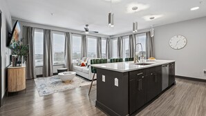 Eine moderne Küche mit Kochinsel, einem Essbereich mit einer Couch und einem großen Fenster mit Vorhängen.