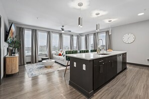 Eine moderne Küche mit Kochinsel, einem Essbereich mit einer Couch und einem großen Fenster mit Vorhängen.