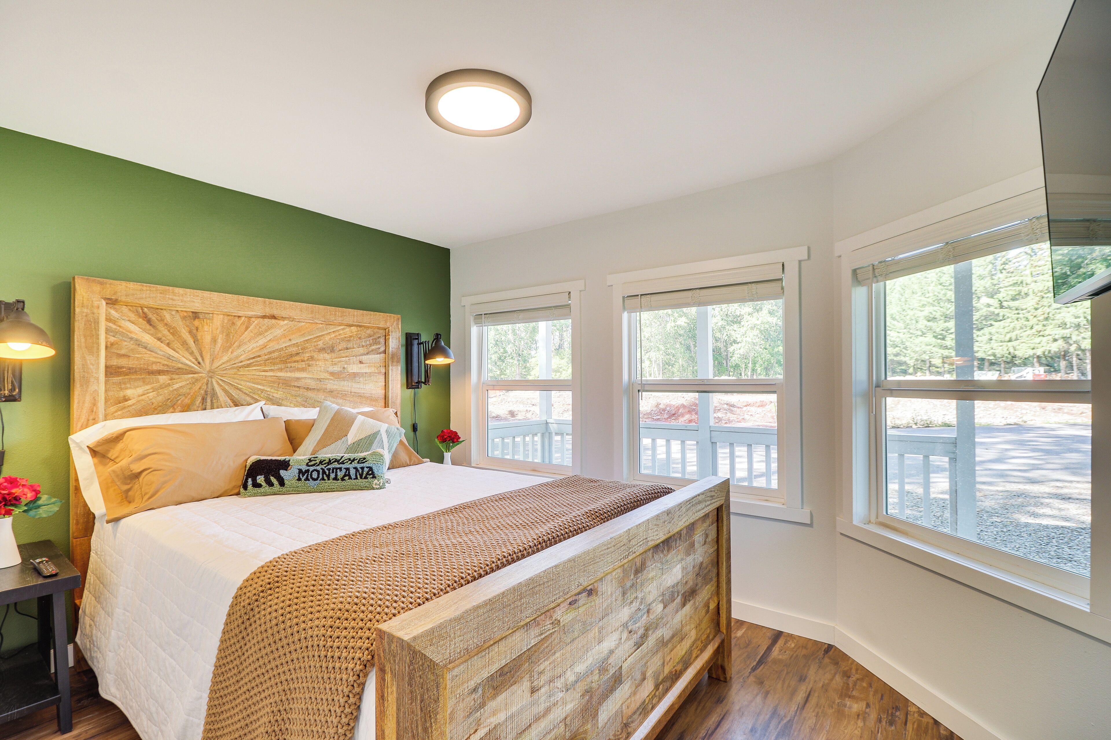 Une chambre à coucher avec une tête de lit en bois, une grande fenêtre et une vue sur l’extérieur.