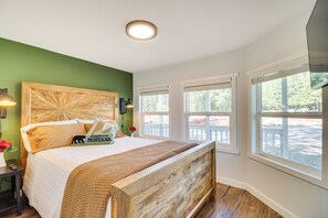 Ein Schlafzimmer mit einem großen Bett, grünen Wänden und mehreren Fenstern.