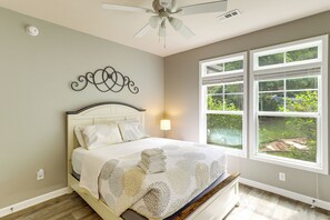 Ein Schlafzimmer mit Bett, Deckenventilator, Fenster mit Jalousien und einer Wanddekoration.