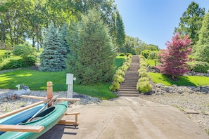 A concrete pathway leading to a staircase surrounded by lush greenery and a row of canoes.