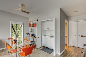 Una cocina moderna con armarios blancos, una mesa de comedor de vidrio y sillas anaranjadas.