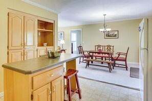 A kitchen with wooden cabinets, a dining table with chairs, and a refrigerator. - 7 Mi to Lake Chatuge! Family Home w/ Office & Yard (Hayesville)