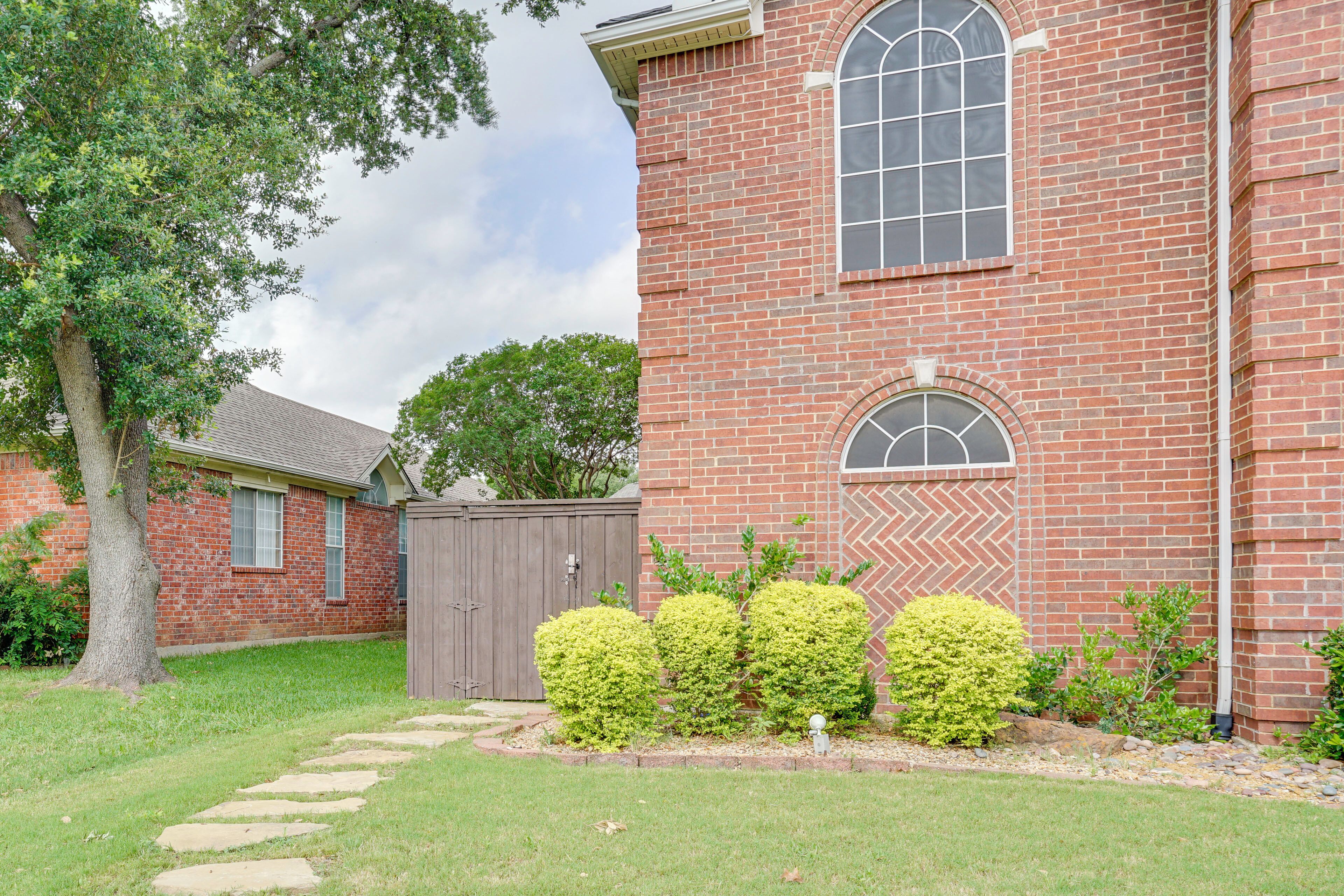 A brick building with a large window, a wooden fence, and a well-maintained lawn with stepping stones.