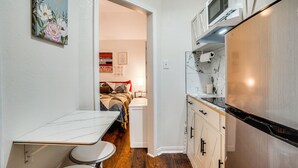 Eine kleine Küche mit Kühlschrank, Mikrowelle und einer Essecke mit Tisch und Stühlen.