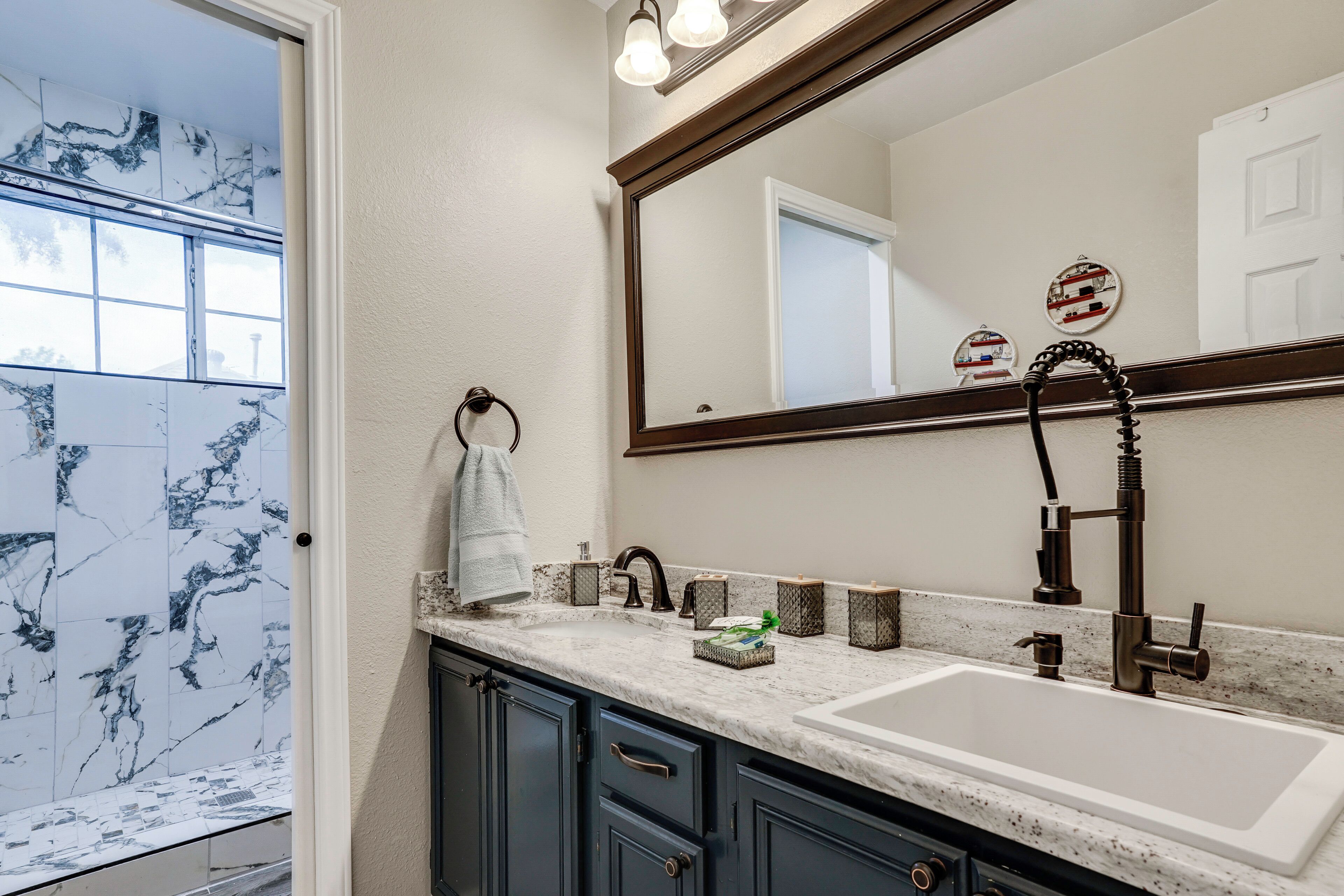 Un baño con salpicadero de mármol, un espejo grande, un lavabo con grifo moderno y un perchero para toallas.