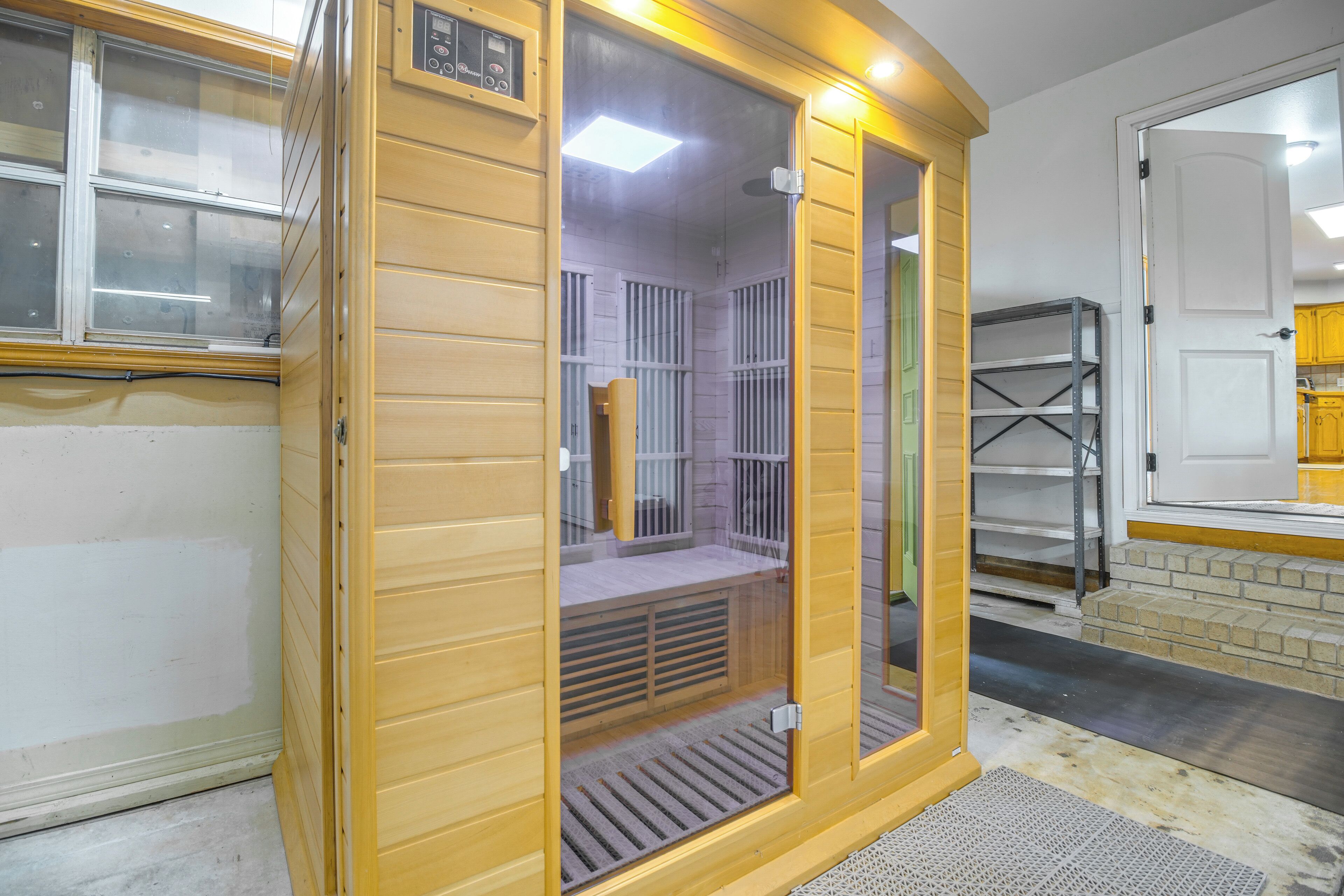 A sauna with a wooden exterior, a glass door, and a bench inside.