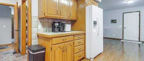 A kitchen with wooden cabinets, a white refrigerator, and a trash can.