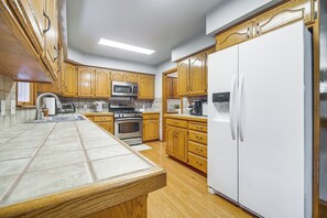 A kitchen with wooden cabinets, a white refrigerator, a microwave, and an oven.
