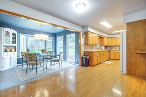 A spacious kitchen with wooden cabinets, a dining area with chairs, and a large window.