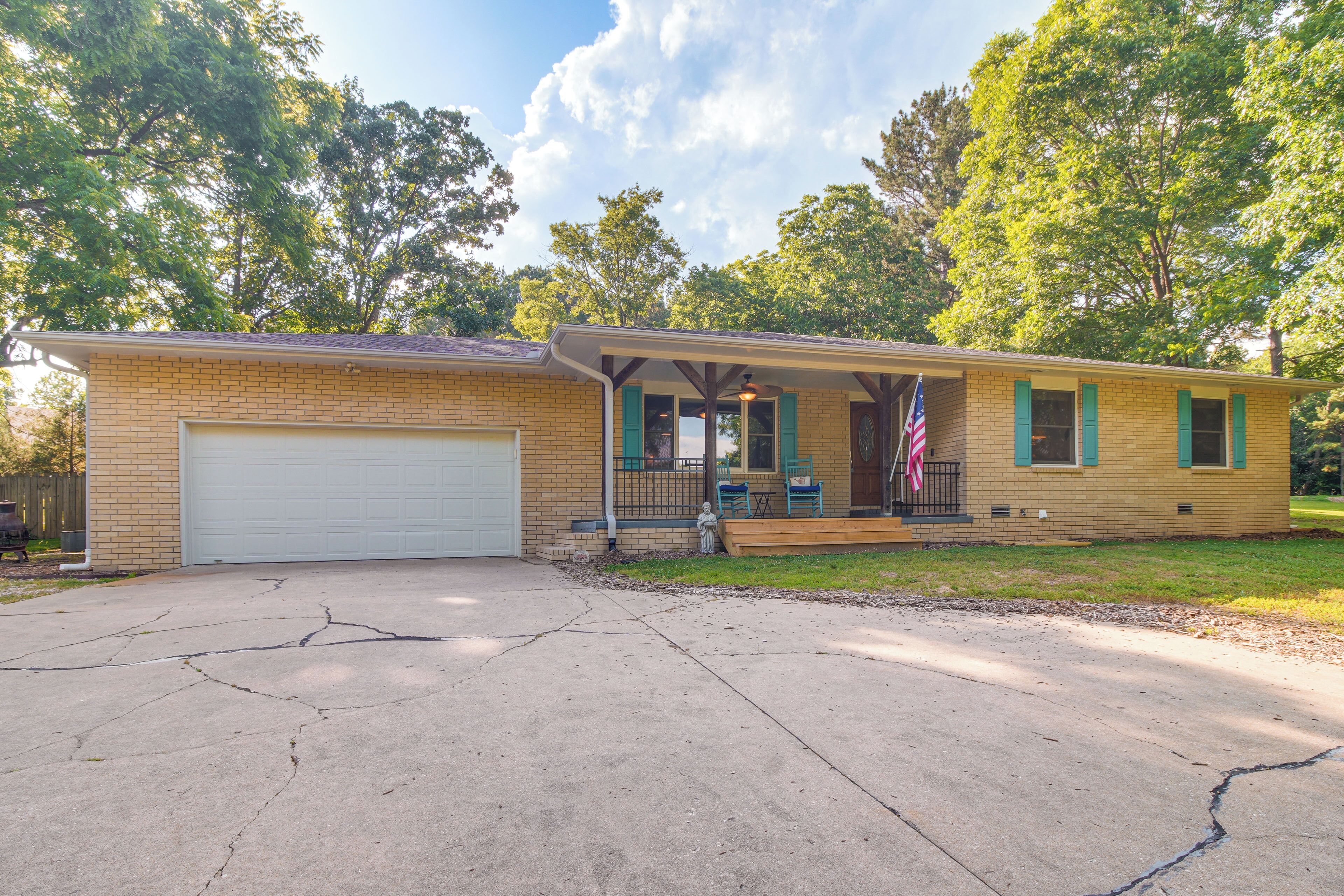 A single-story brick house with a garage, a covered porch, and a small front yard.