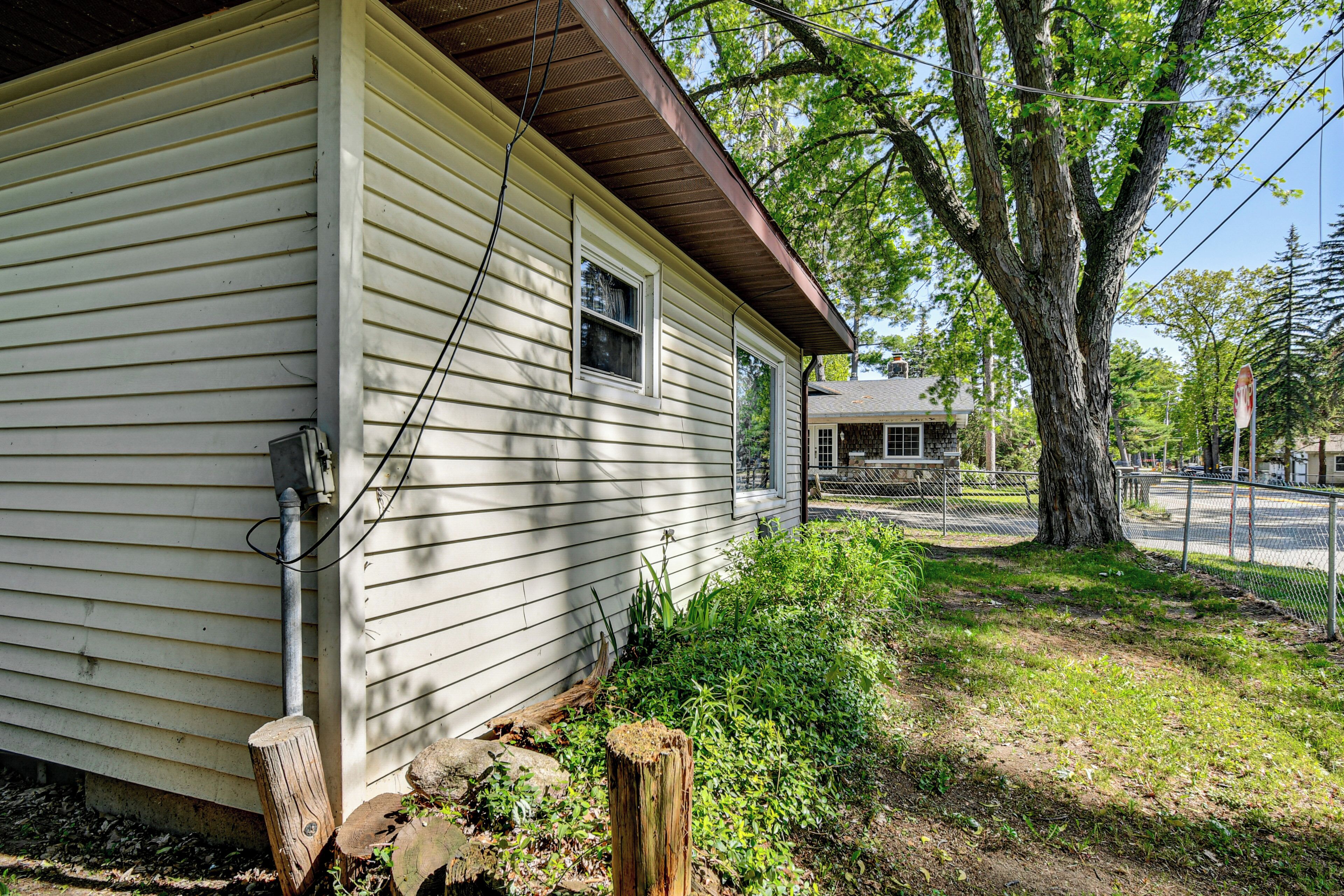 A house with a sloped roof, a visible electrical box, and a tree in the yard.
