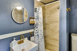 A bathroom with a sink, mirror, and shower curtain.