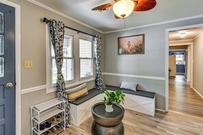 A hallway with a bench, a plant on a table, and a door. - Shop, Dine, Walk to Houghton Lake! Family Getaway (Prudenville)