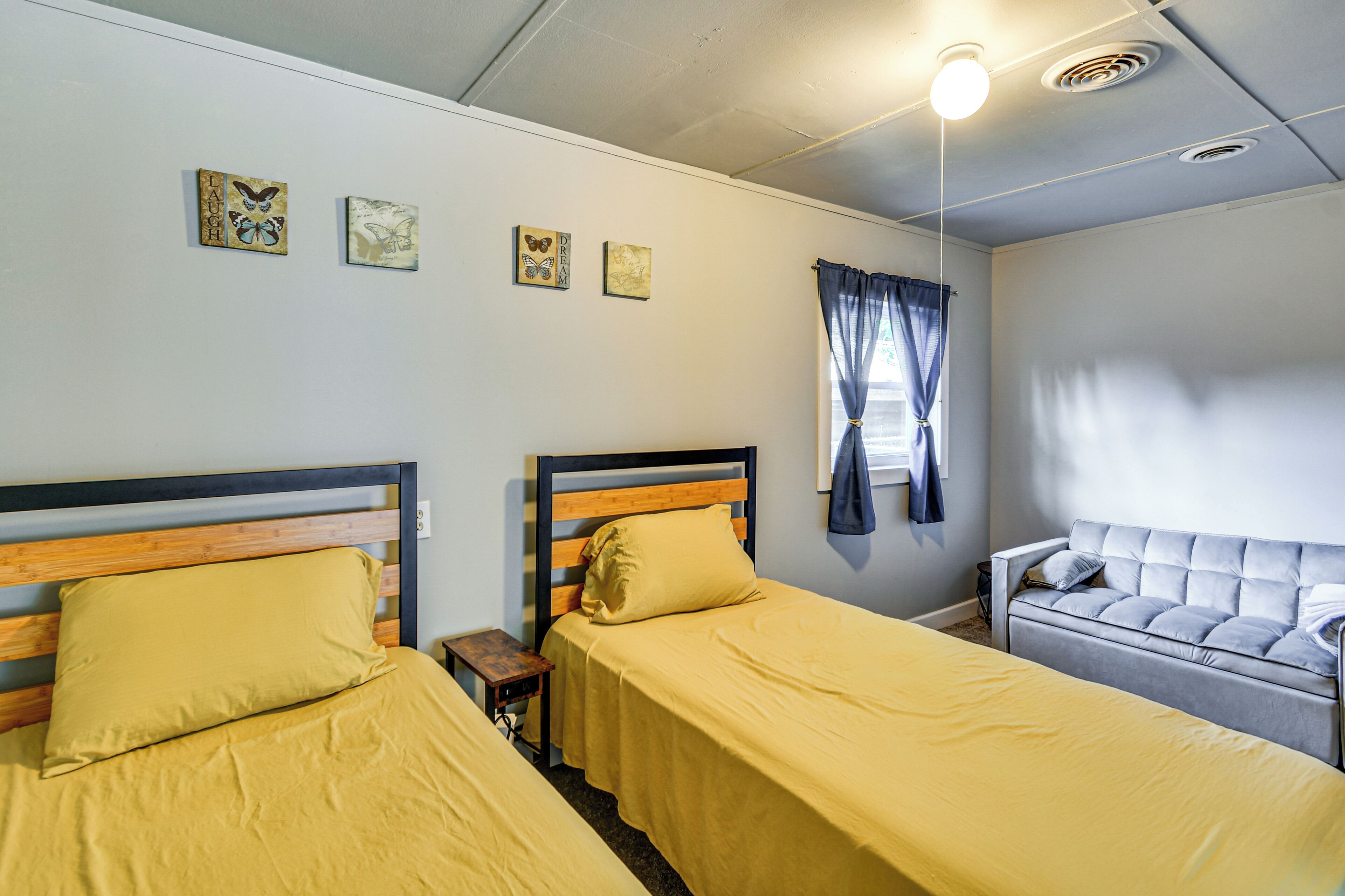 Ein Zimmer mit zwei Betten, einem Schlafsofa, einem kleinen Tisch und Bildern an der Wand.