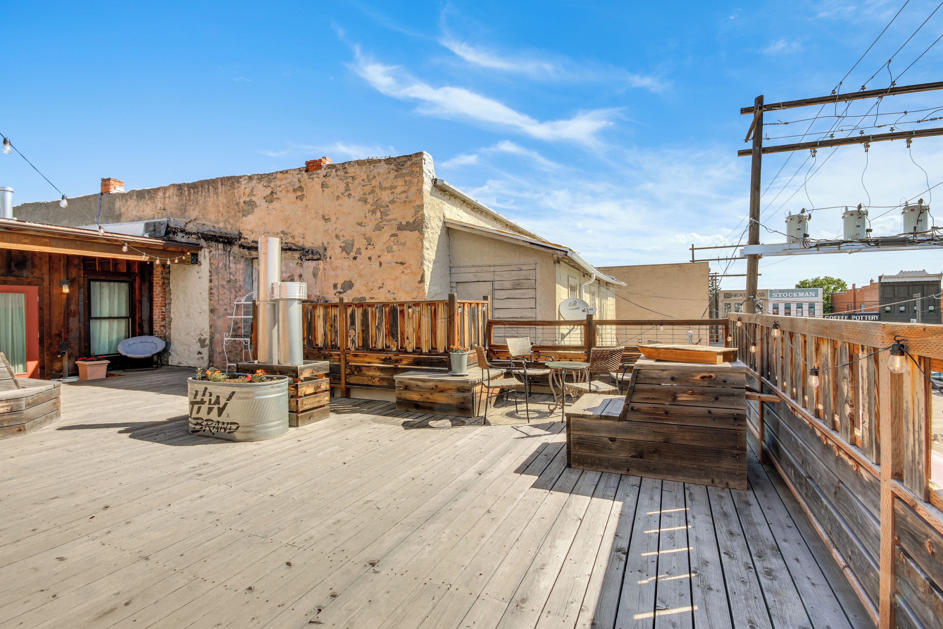 A rooftop deck with wooden furniture, a planter, and a sign for a coffee shop.
