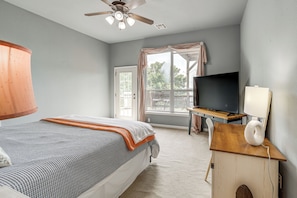 A bedroom with a bed, a ceiling fan, a TV, and a desk with a lamp. - Sunset View Deck! Lake Eufaula Family Getaway (Stigler)