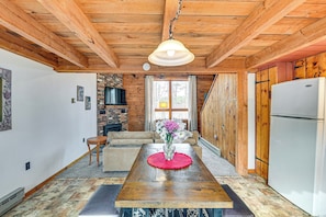 A wooden interior with a dining table, sofa, and a white refrigerator. - Woodland Views: Romantic Hudson Valley Hideaway (Earlton)