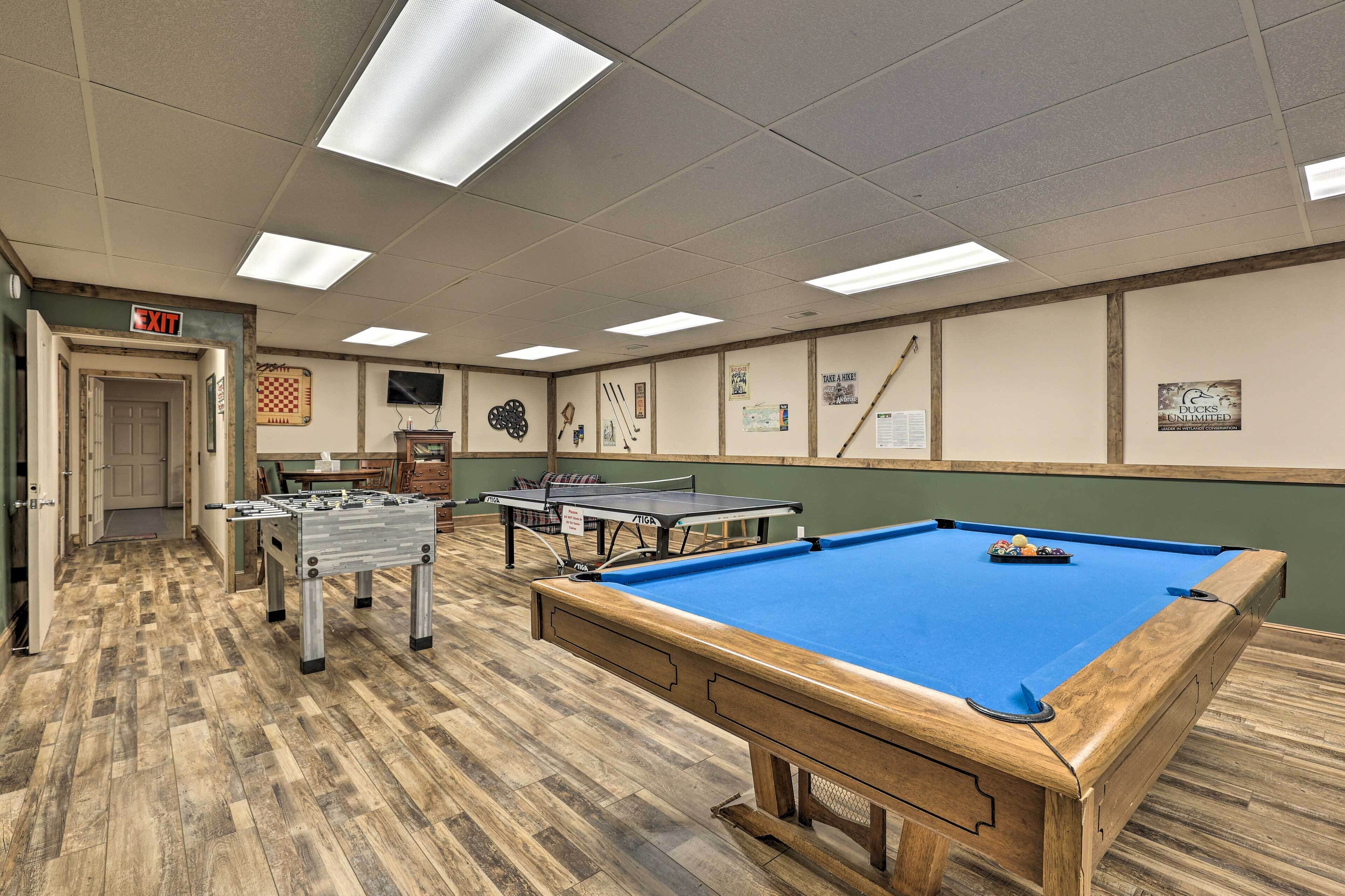 A recreational room with a pool table, foosball table, and ping pong table.