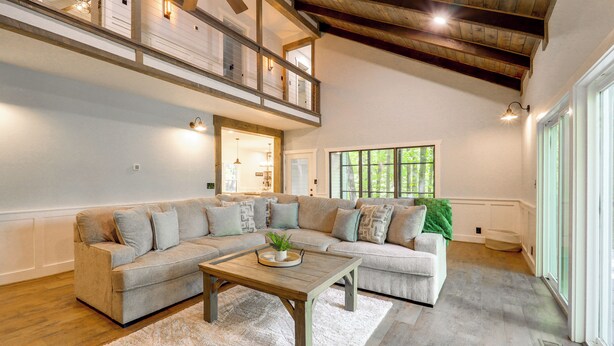 A spacious living room with a sectional sofa, a wooden coffee table, and a high ceiling with exposed beams. - Resort Perks & Game Room! Group Escape in Deep Gap (Deep Gap)